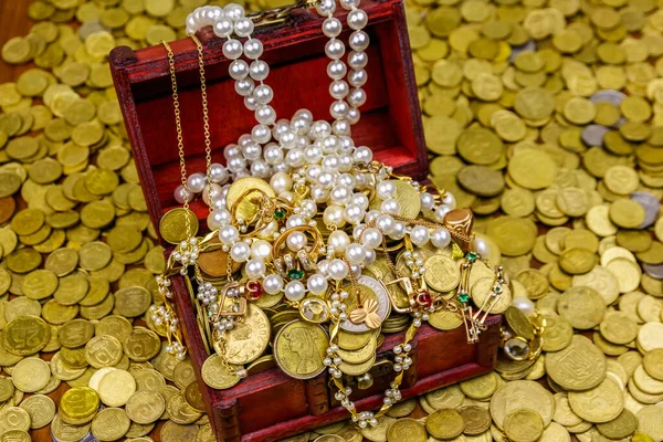 Vintage treasure chest full of gold coins and jewelry on a background of golden coins