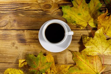Bir fincan kahve ve sonbahar akçaağaç yaprakları ahşap masada. Üst Manzara. Sonbahar konsepti