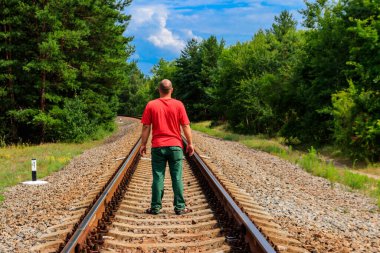 Yalnız adam tren yolunda yürüyor.