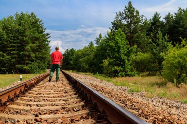 Yalnız adam tren yolunda yürüyor.