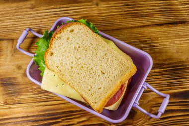 Tahta bir masanın üzerinde sandviçlerle beslenme çantası. Üst görünüm