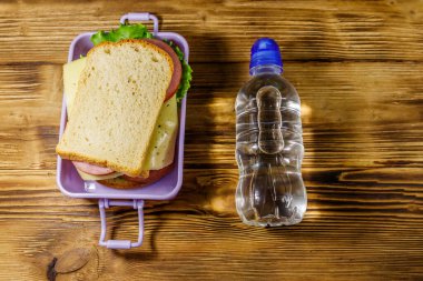 Sandviç ve ahşap bir masada bir şişe su ile beslenme çantası. Üst görünüm