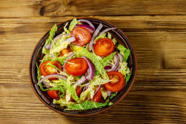 Savoy lahanalı sağlıklı salata, vişneli domates, kırmızı soğan ve ahşap masada zeytinyağı. Üst görünüm