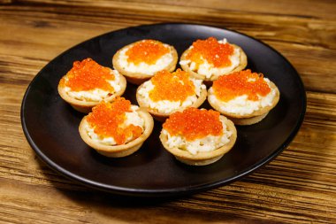 Kırmızı havyarlı turta ve ahşap bir masada yumuşak peynir.