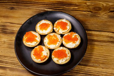 Kırmızı havyarlı turta ve ahşap bir masada yumuşak peynir.