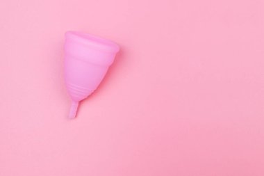 Pembe arka planda tekrar kullanılabilir silikon adet kupası. Üst görünüm, boşluğu kopyala. Kadın hijyeni, jinekoloji ve sağlık kavramı