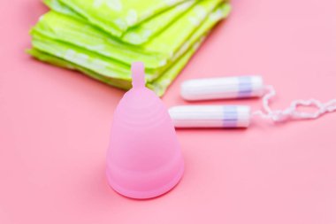 Pembe arka planda hijyenik ped, tampon ve regl kupası. Kritik günler, regl dönemi, kadın hijyeni