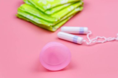 Pembe arka planda hijyenik ped, tampon ve regl kupası. Kritik günler, regl dönemi, kadın hijyeni