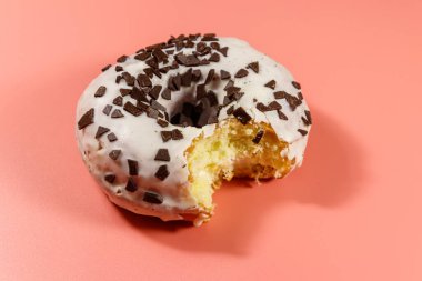 Pembe arka planda ısırılmış lezzetli donut.