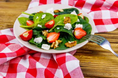 Tahta masada çilekli, ıspanaklı, cevizli ve peynirli taze sağlıklı salata.
