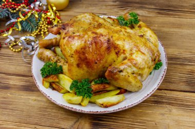 Tavuğun tamamını patates ve Noel süslemeleri ile ahşap bir masada pişirdim.