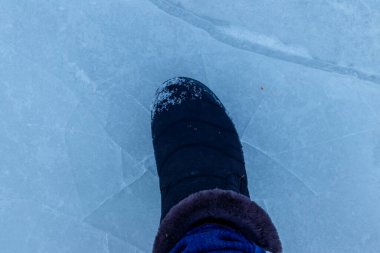 Kırık doğal göl buz dokusunun üzerinde duran ayak. Donmuş suya tehlikeli çıkış kavramı
