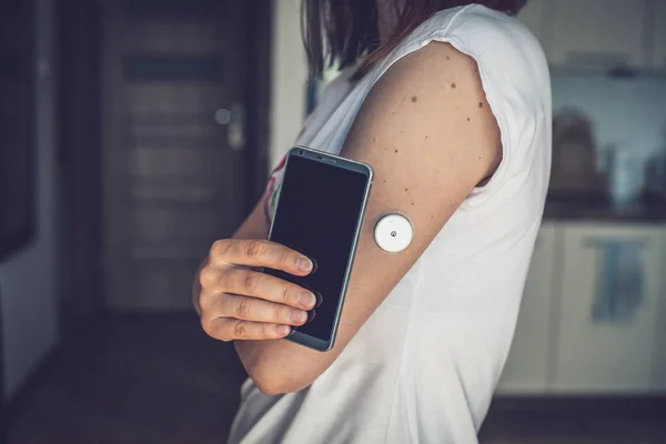 Uzak sensör ve cep telefonu ile glikoz seviyesini kontrol kadın, kan olmadan sensör kontrol glikoz düzeyleri. Diyabet tedavisi.