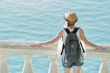 Balkonda duran ve denize bakarak şapkalı kız. Arkadan Görünüm