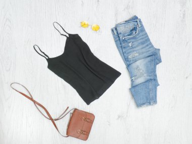 Siyah kolsuz bluz, yırtık kot pantolon, çanta ve güneş gözlüğü. Moda kavramı