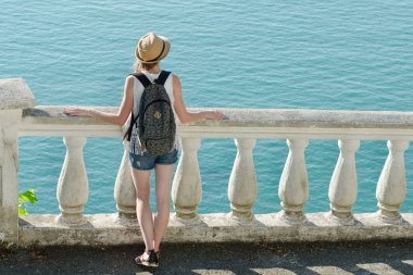 Balkonda duran ve denize bakarak şapkalı kız. Arkadan Görünüm