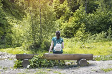 Kız ormanın hayran sırt çantası ile. Arkadan görünüm. Yaz güneşli gün