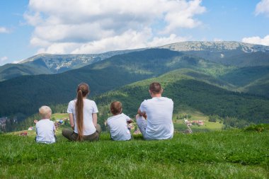 Aile tatili. Anne ve iki oğlu dağların manzarasına hayran kalacaksınız. Arkadan görünüm. Güneşli yaz gün