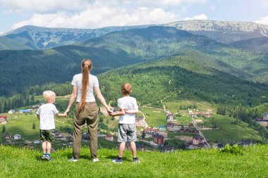 Aile tatili. Anne ve iki oğlu duran ve dağ manzarası. Arkadan görünüm. Güneşli yaz gün