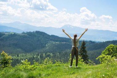 Kız el ile ayakta. Orman ve dağlar içinde belgili tanımlık geçmiş. Arkadan görünüm