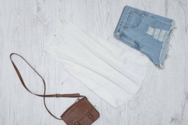 Beyaz kolsuz bluz, el çantası ve yırtık kot şort. Moda kavramı