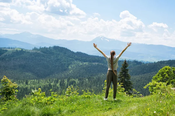 Kız el ile ayakta. Orman ve dağlar içinde belgili tanımlık geçmiş. Arkadan görünüm