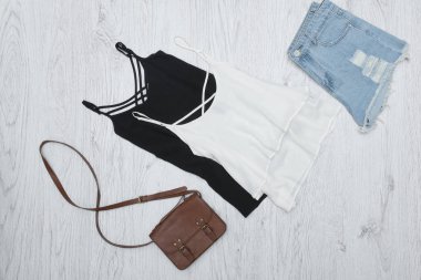 Siyah ve beyaz kolsuz bluz, el çantası ve yırtık kot şort. Moda kavramı