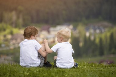 İki erkek bir tepe üzerinde oturmak ve eğlenin. Arkadan görünüm