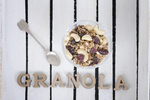 Fincan yoğurt, granola, bir çay kaşığı ve Granola yazıt. Arka plan beyaz tabaklar