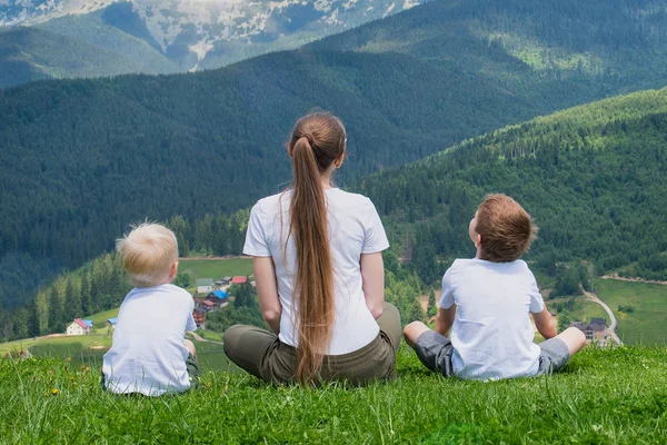 Aile tatili. Anne ve iki oğlu dağın manzarayı. Arkadan görünüm. Güneşli yaz gün