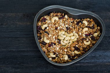 Bir fırın tepsisine kaju granola. Siyah ahşap masa