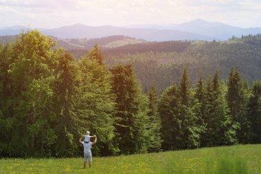 Onun omuzlarında küçük oğlu olan babası. Yaz güneşli gün. Arkadan görünüm