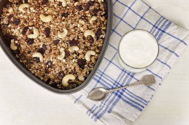 Granola bir pişirme levha ve hafif beyaz zemin üzerine yoğurt.