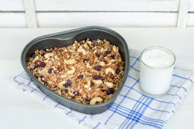 Granola bir pişirme levha ve hafif beyaz zemin üzerine yoğurt.