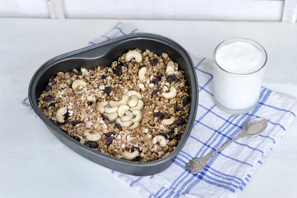 Granola bir pişirme levha ve hafif beyaz zemin üzerine yoğurt.