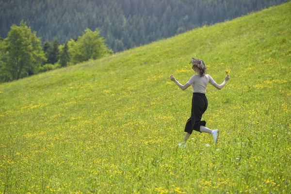 Kızla bir buket çiçek çayır üzerinde çalışıyor. Güneşli yaz gün