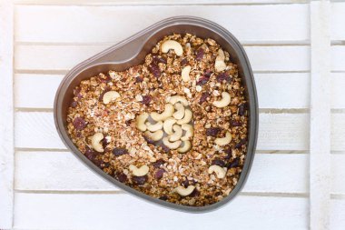 Granola ışık beyaz bir arka plan üzerinde şeklinde bir pişirme levha kalp.