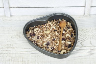 Granola ışık beyaz bir arka plan üzerinde şeklinde bir pişirme levha kalp.