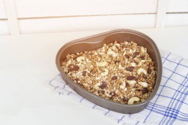 Granola ışık beyaz bir arka plan üzerinde şeklinde bir pişirme levha kalp.