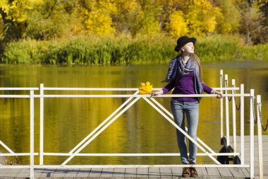 Kız şapka ayakta üstünde belgili tanımlık rıhtım. Sonbahar, güneşli.