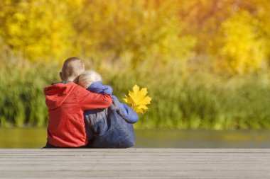 İki erkek iskelede oturuyor. Sonbahar. Arkadan Görünüm.