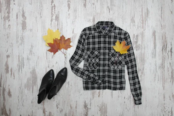 Black checkered shirt and maple leaves. Fashionable concept