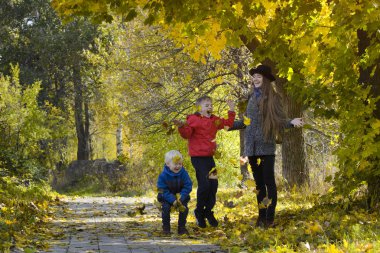 Anne ve oğulları yaprakları at. Sonbahar Park.