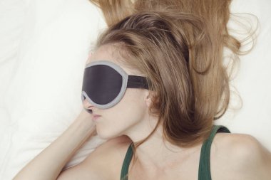 Genç kadın bir maske uyku uyuyor. Gevşeme