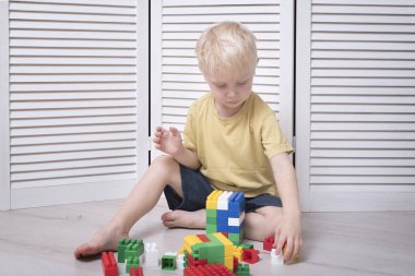 Küçük sarışın çocuk renkli tasarımcı yapıyor.