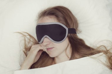 Genç kadın bir maske uyku uyuyor. Gevşeme