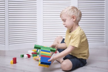 Küçük sarışın çocuk renkli tasarımcı yapıyor.