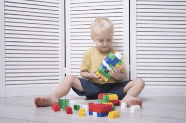 Küçük sarışın çocuk renkli tasarımcı yapıyor.