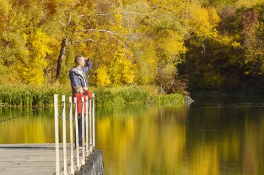 Baba ve oğul iskelede nehir kıyısında durmak. Güneşli bir sonbahar gün