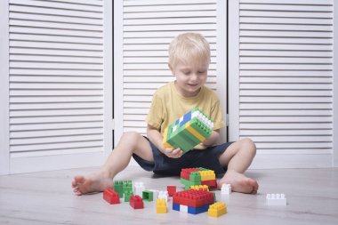 Küçük sarışın çocuk renkli tasarımcı yapıyor.